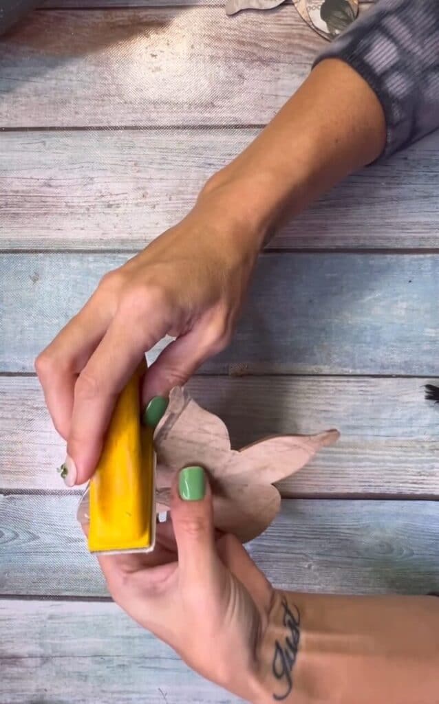 Using a gator sander to sand off the excess vintage scrapbook paper.