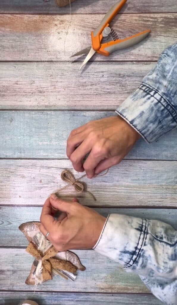Tie a piece of twine around the center of the twine bow to make a figure 8 bow.