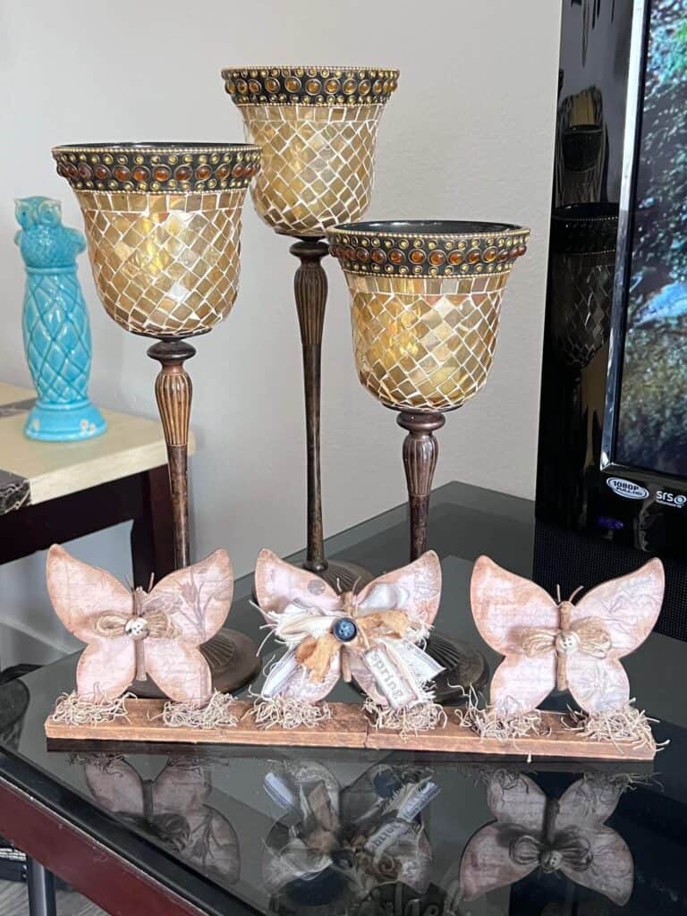 3 Wood Butterfly shelf sitter with a vintage vibe with a spring hangtag and twine and fabric bows, sitting on a base with spanish moss.
