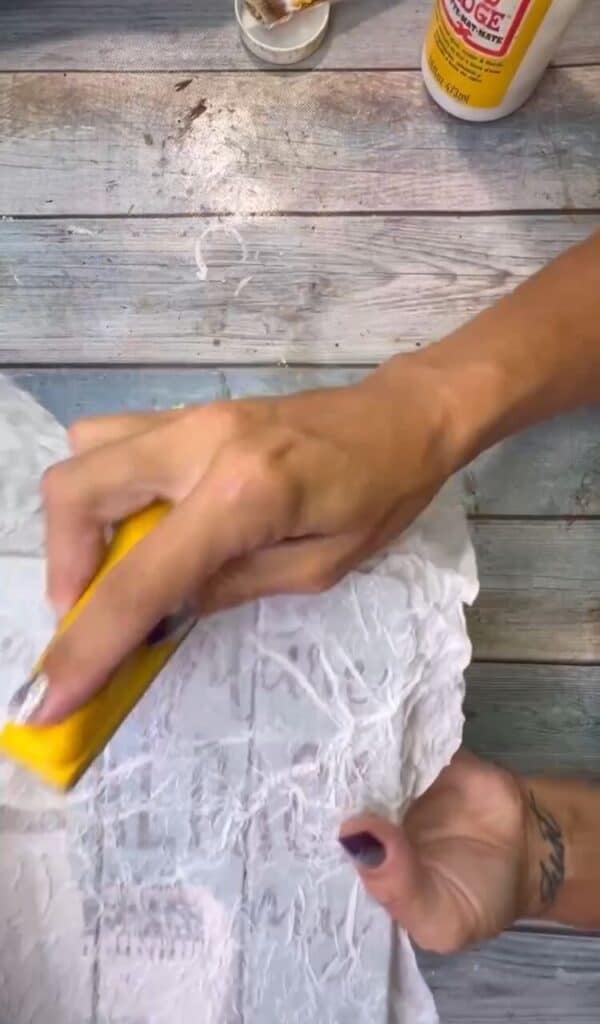 Using a gator sander or sanding block to sand off the excess tissue paper from the edges.