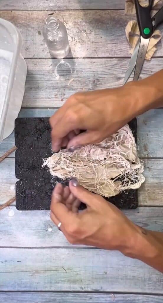 Shaping the fabric into the shape of a ghost on the background.