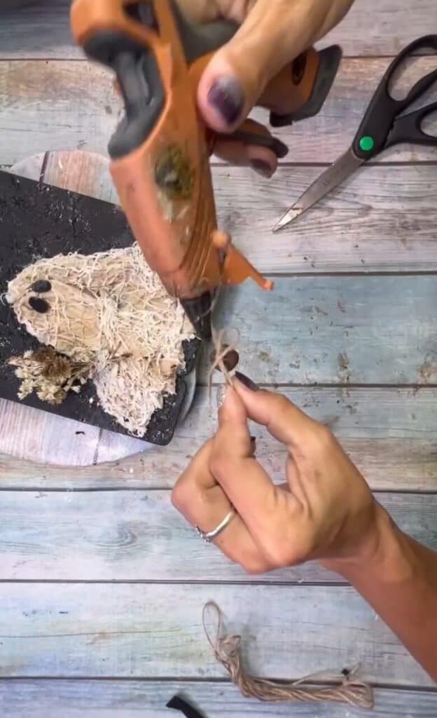 Glue a twine bow with a rusty bell to the flower bouquet.