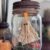 Floating Ghost in a mason Jar made from muslin and creepy cloth and hanging by fishing line with a tea light at the top to give it a spooky cute halloween vibe. The bottom has green reindeer moss, a gravestone that says RIP and a small pumpkin.