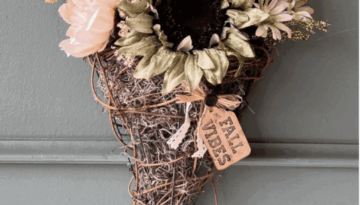 Fall floral grapevine wreath basket door decor hanging on a sage green front door with pretty fall flowers, a sweater pumpkin pick and a hangtag that says "Fall vibes".