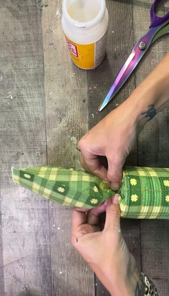 Pinching the napkin together at the top of the hat.