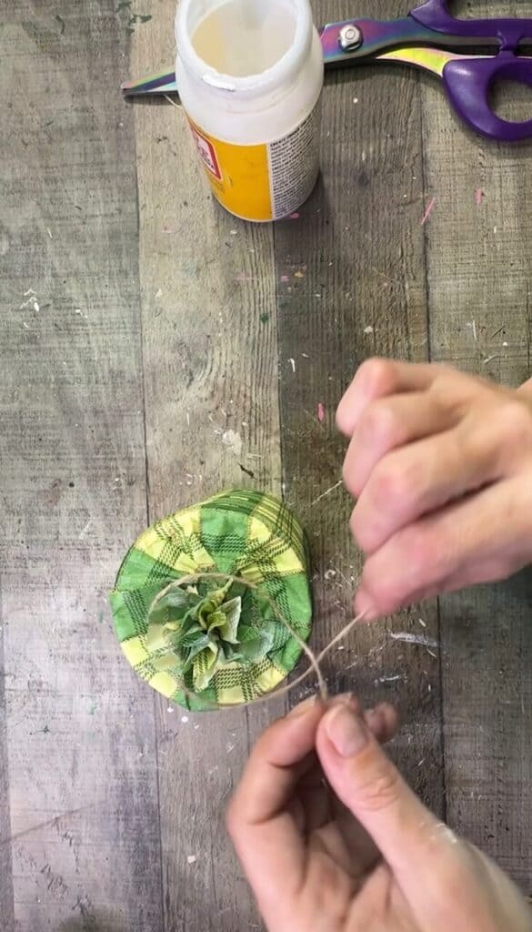 Tying a twine bow around the top of the hat.