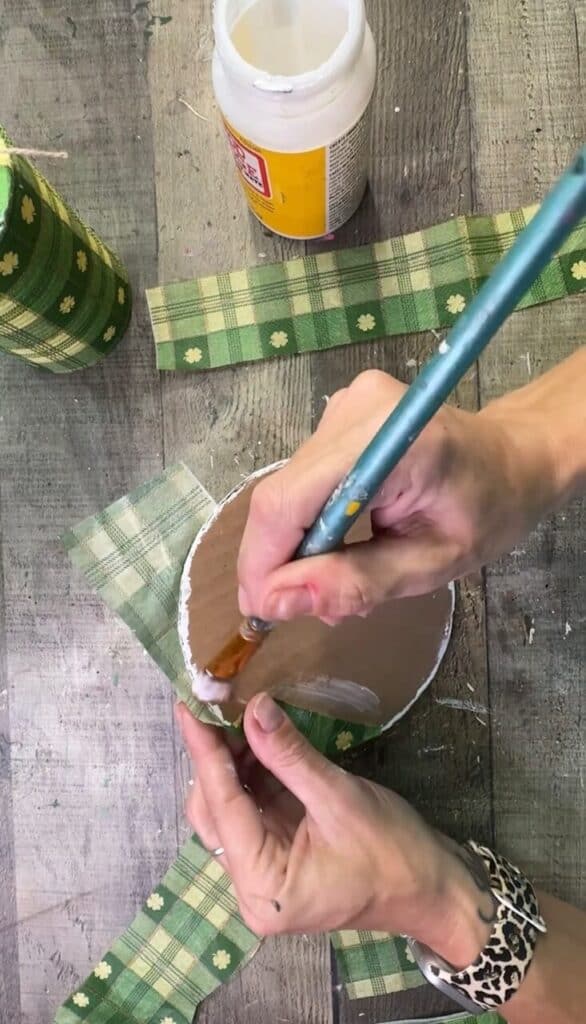 Decoupaging the green check napkin to the cardboard brim.
