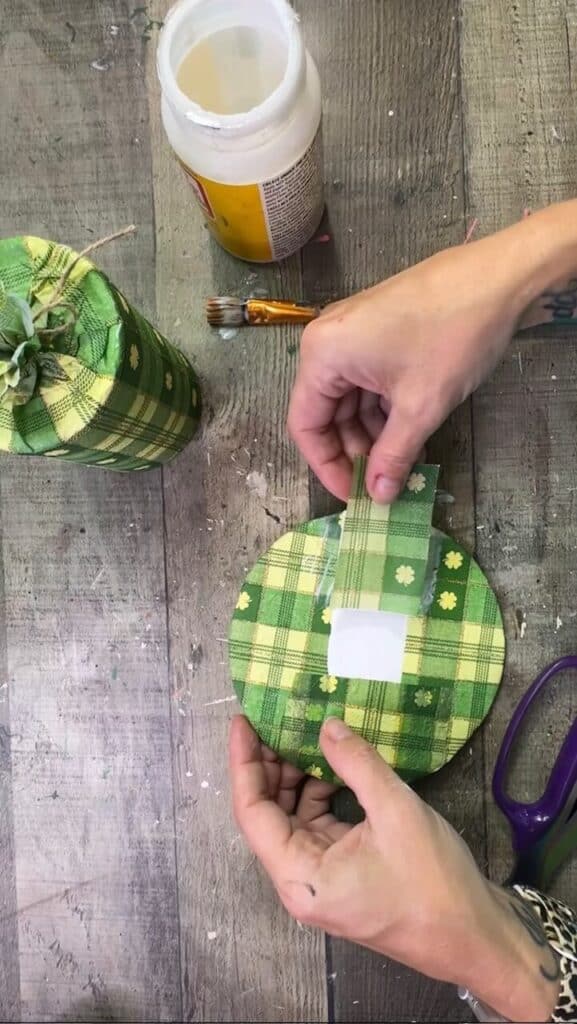 Decoupaging the green check napkin to the cardboard brim.